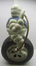 Michelin Man Sitting on a Tire with Hose Blowing Up The Tire