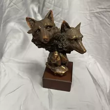 Two headed bronze colored wolf heads statue on a wood base